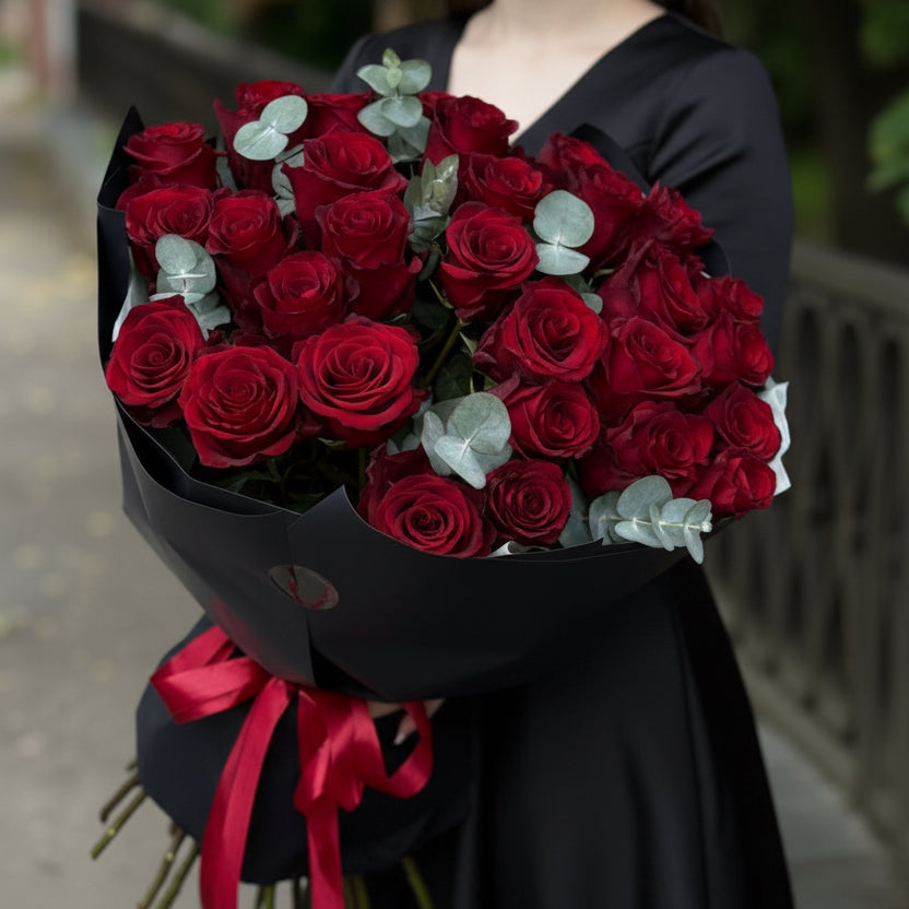 Valentine’s Day bouquet of fresh red roses with eucalyptus, elegant black wrap and red ribbon by Velvet Butterfly Flower Studio in Houston.