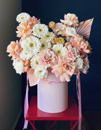 A luxury flower arrangement in a hatbox filled with roses gerberas and ranunculus 