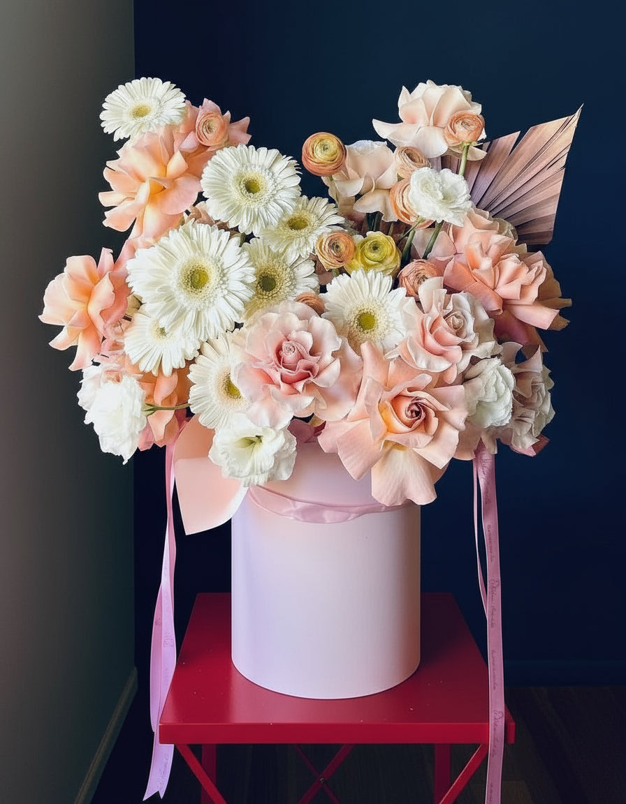 A luxury flower arrangement in a hatbox filled with roses gerberas and ranunculus 