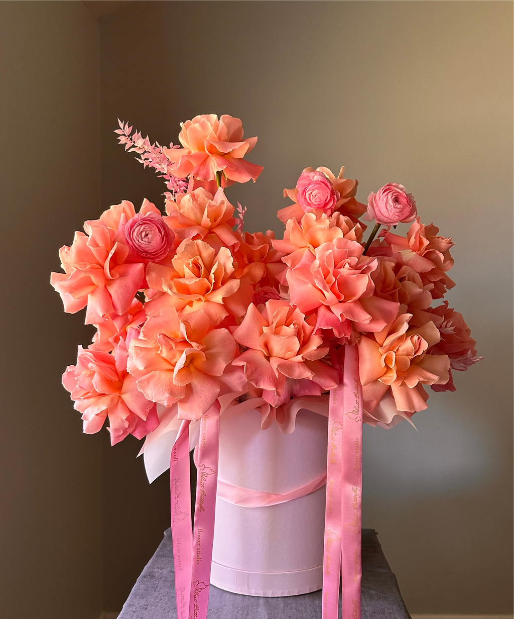 Bouquet of pink flowers in a white box with pink ribbons 