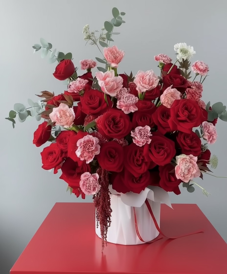 Bouquet of red and pink carnations in a white hatbox