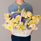 yellow roses and purple hydrangeas in a basket